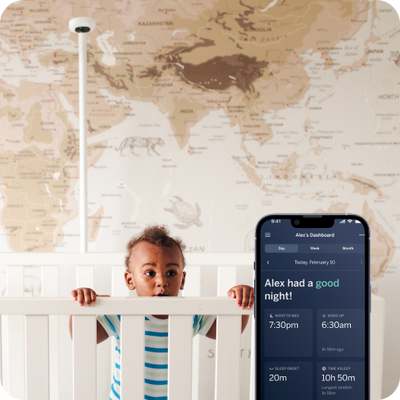 child over looking over crib with nanit Pro camera wall mount in background and mobile display in front