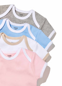 Four baby onesies are arranged in a fan shape. The onesies are gray, blue, white with beige trim, and pink, all with white trim and labeled “nanit” at the neckline, displayed on a white background.